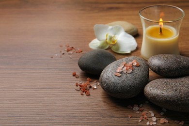 Photo of Beautiful composition with spa stones and burning candle on wooden table. Space for text