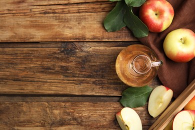 Photo of Natural apple vinegar and fresh fruits on wooden table, flat lay. Space for text