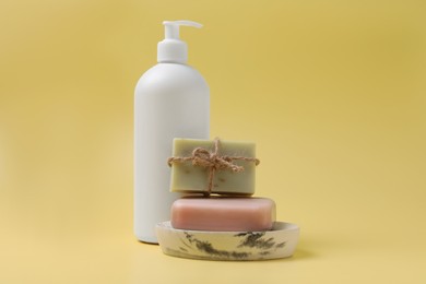 Photo of Soap bars and bottle dispenser on yellow background