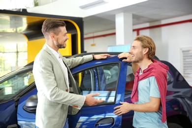 Salesman with customer in modern car dealership