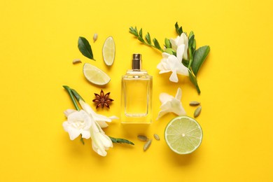 Photo of Flat lay composition with bottle of perfume and fresh citrus fruits on yellow background