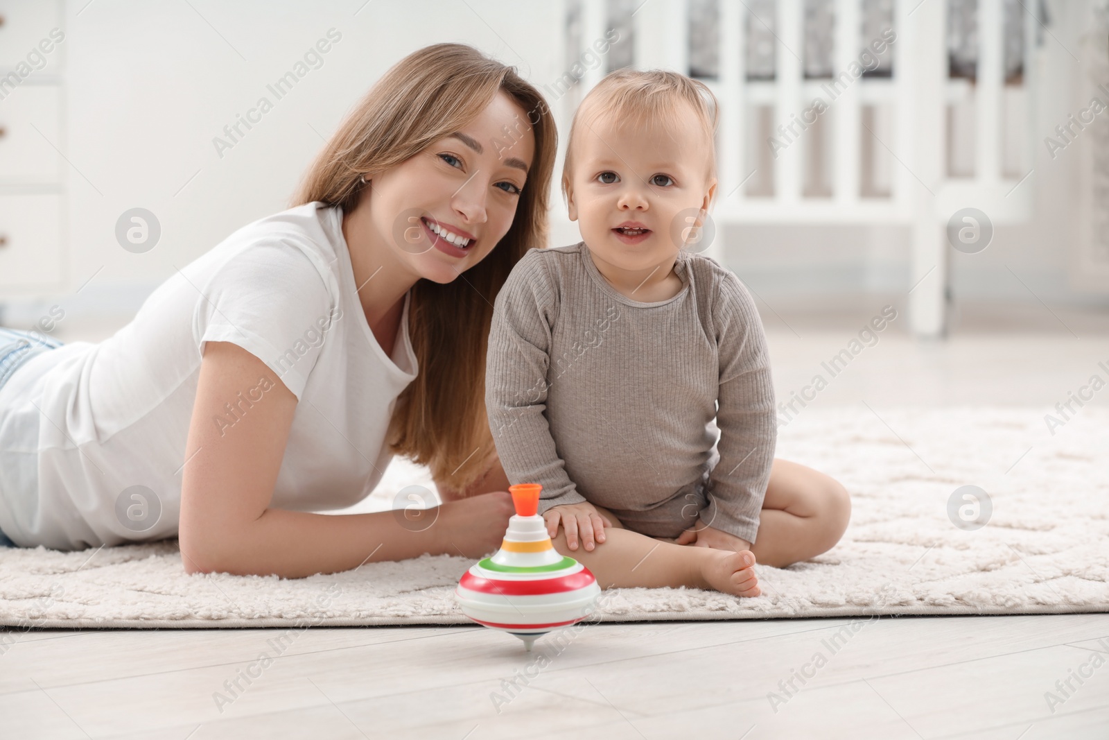 Photo of Children toys. Happy mother with her little son and spinning top on rug at home