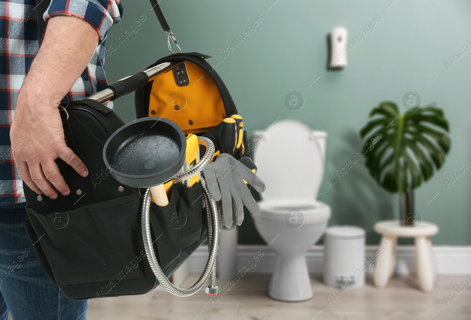 Image of Plumber with bag of instruments in bathroom, closeup. Space for text