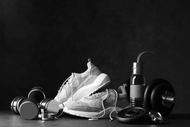 Photo of Gym equipment and accessories on stone floor against dark background
