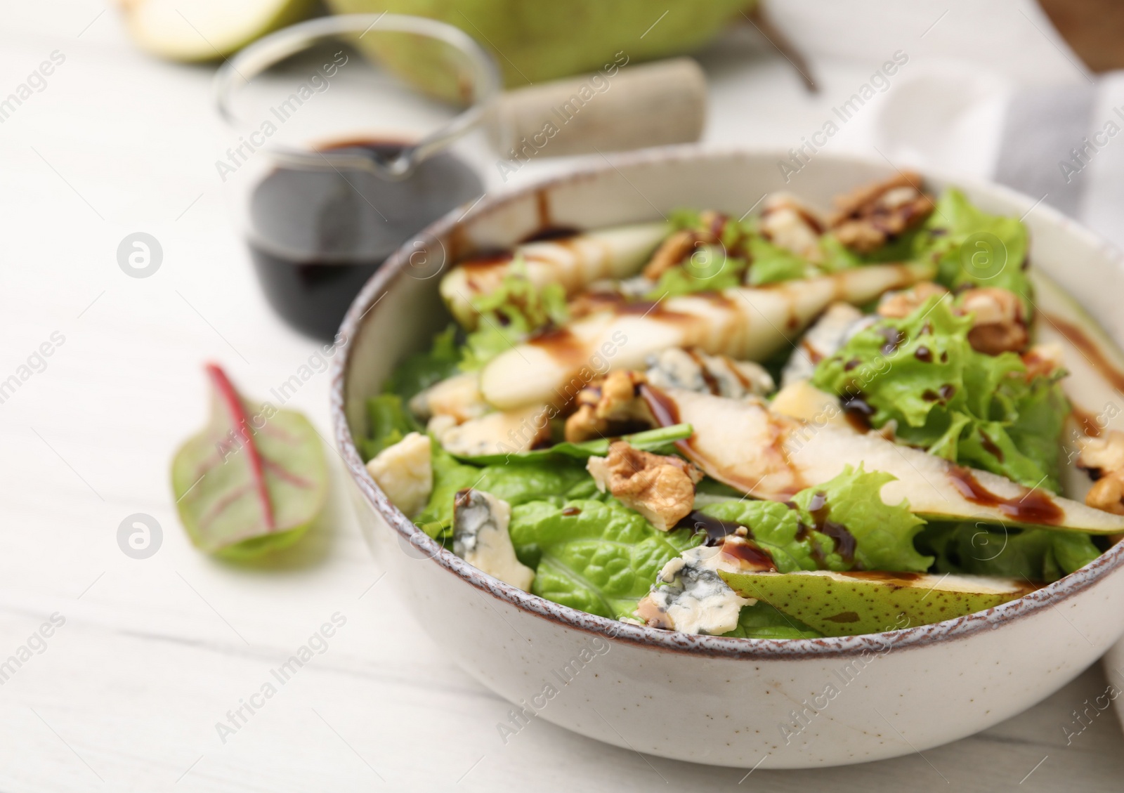 Photo of Delicious pear salad with sauce in bowl on white wooden table, closeup