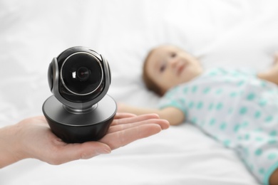 Woman holding baby camera near child on bed. Video nanny