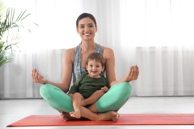 Young woman meditating with her son at home