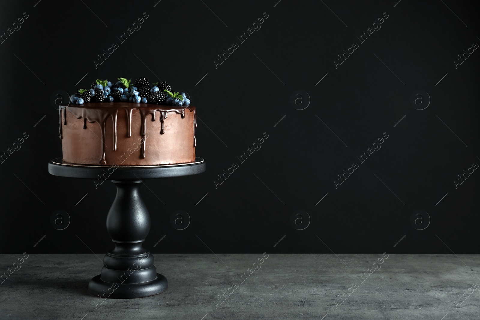 Photo of Fresh delicious homemade chocolate cake with berries on table against dark background. Space for text