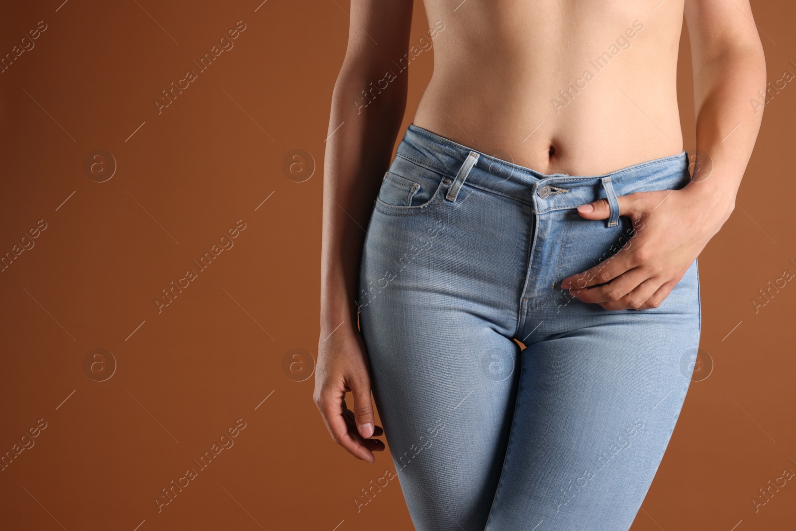 Photo of Woman wearing stylish light blue jeans on brown background, closeup. Space for text