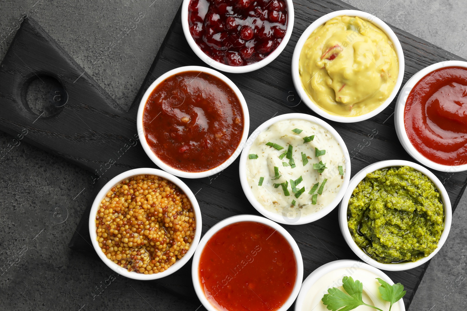 Photo of Different tasty sauces in bowls on grey table, top view