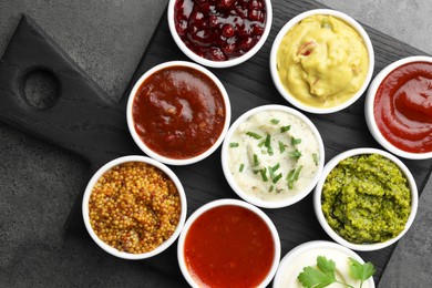 Photo of Different tasty sauces in bowls on grey table, top view