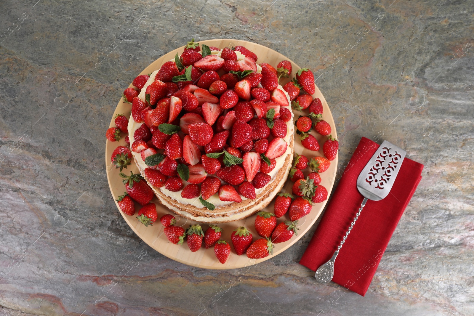 Photo of Tasty cake with fresh strawberries and mint served on gray table, top view