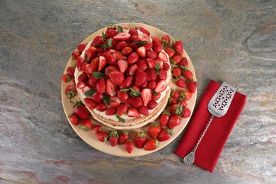 Photo of Tasty cake with fresh strawberries and mint served on gray table, top view