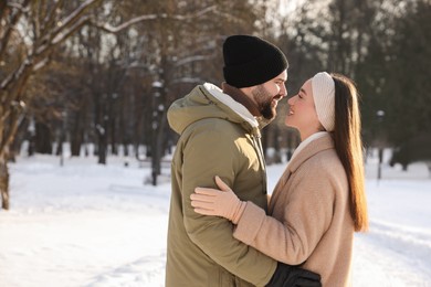 Beautiful happy couple in snowy park on winter day