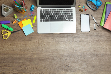 Flat lay composition with laptop, smartphone and stationery on wooden table, space for text. Designer's workplace