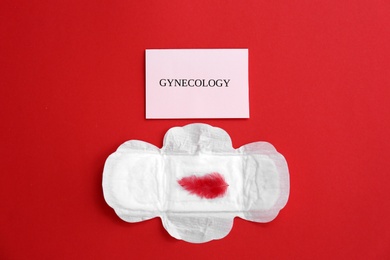 Flat lay composition with menstrual pad and red feather on color background. Gynecological care