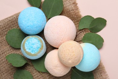 Photo of Bath bombs, eucalyptus leaves and burlap fabric on beige background, flat lay