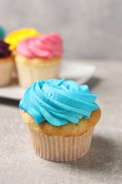 Photo of Delicious cupcakes with bright cream on gray table, selective focus