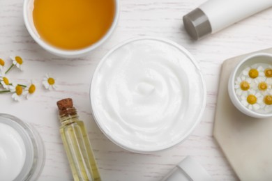 Photo of Body cream and other cosmetics, honey with camomile on white wooden table, flat lay