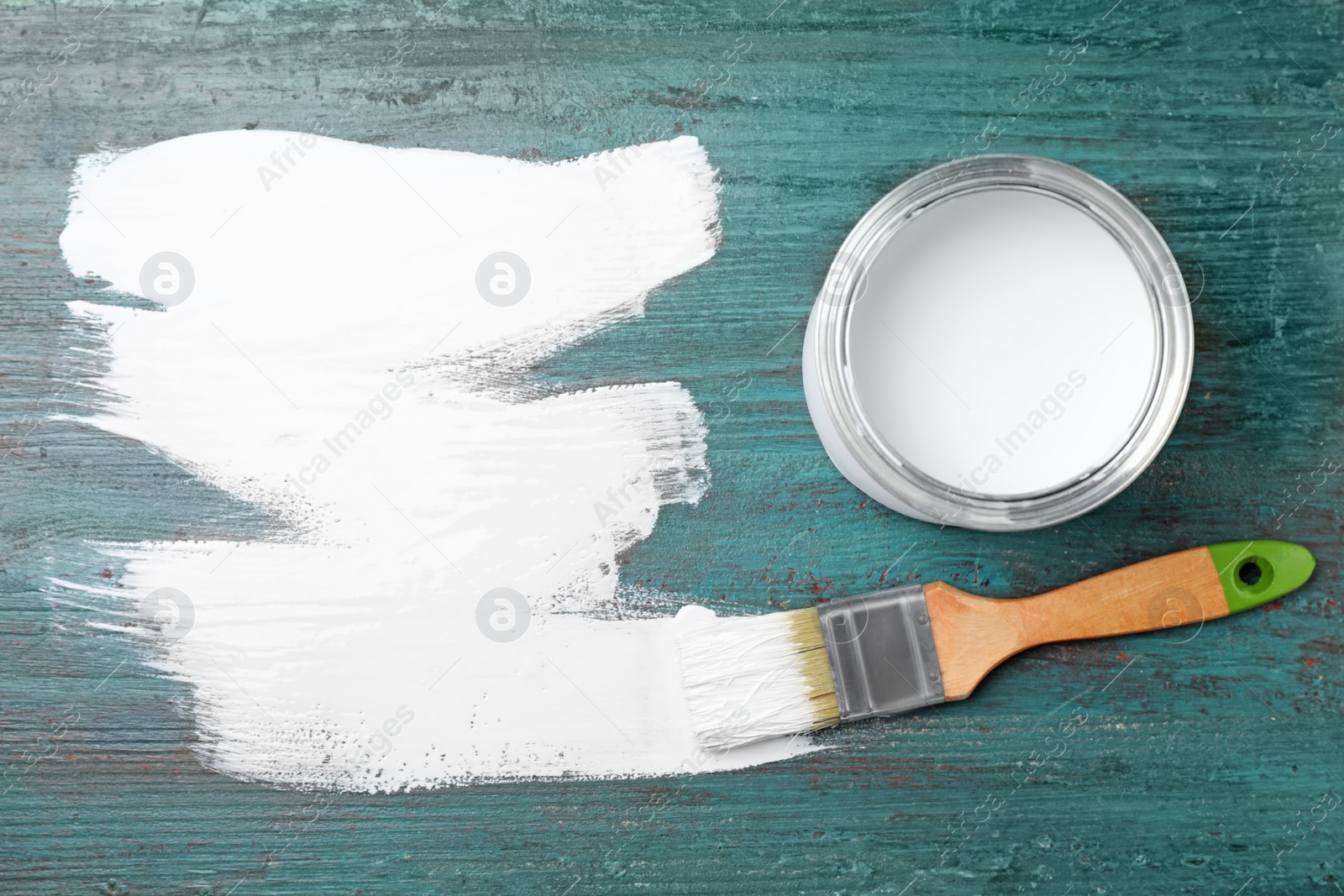 Photo of Can of white paint and brush on teal wooden background, flat lay. Space for text