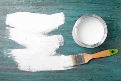 Photo of Can of white paint and brush on teal wooden background, flat lay. Space for text