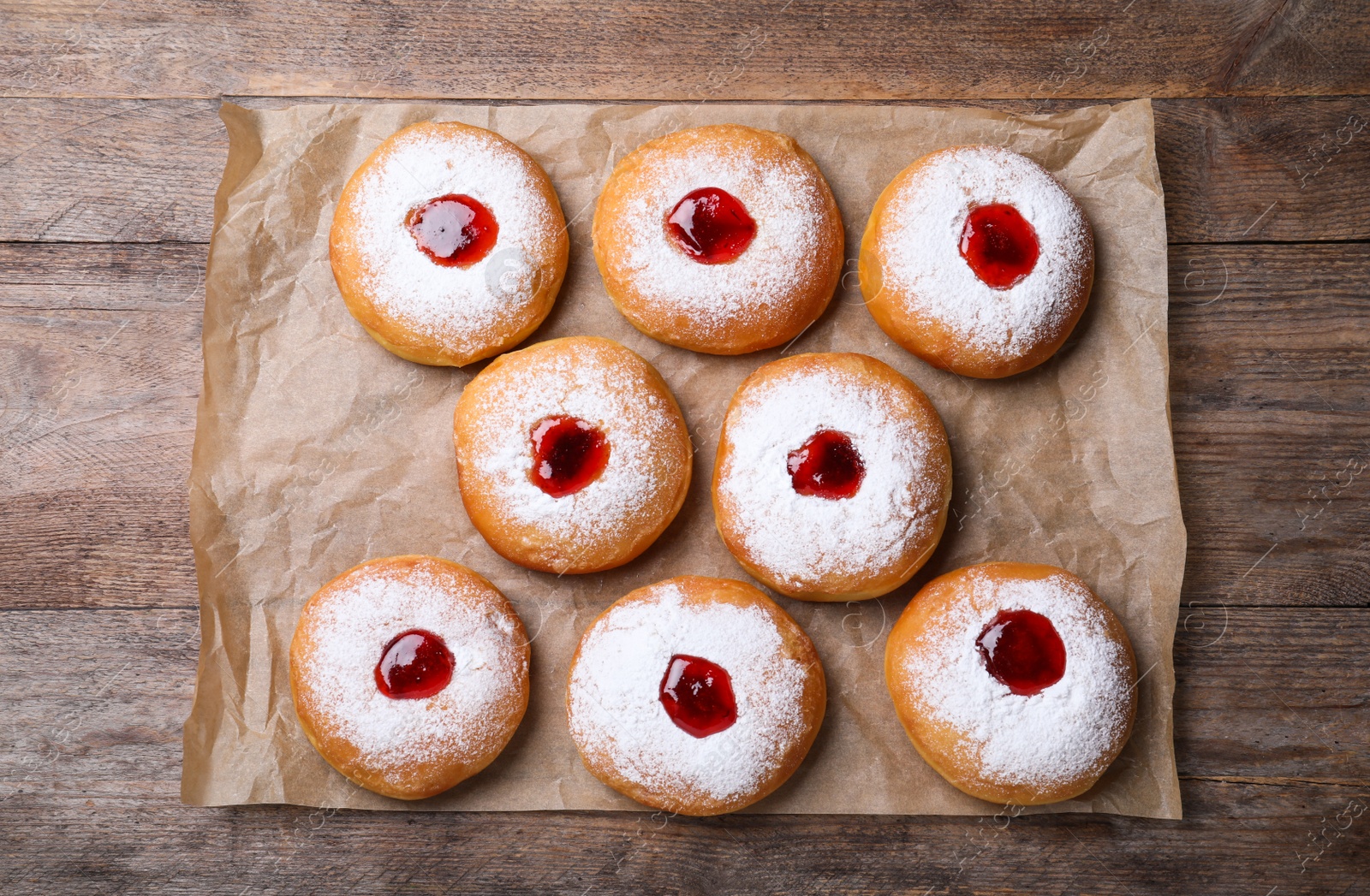 Photo of Hanukkah doughnuts with jelly and sugar powder on wooden table, flat lay