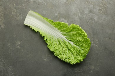 Photo of Fresh Chinese cabbage leaf on gray textured table, top view