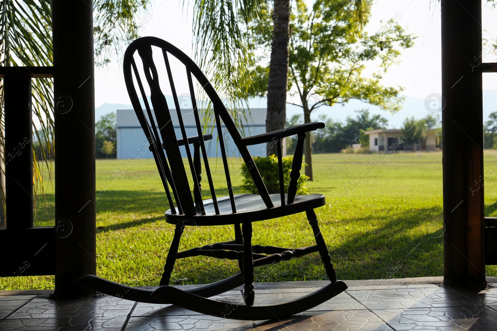 Photo of Terrace with wooden rocking chair near green lawn on sunny day