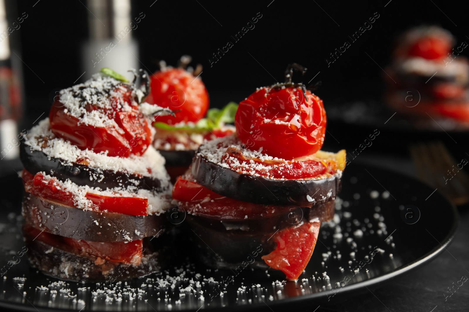 Photo of Baked eggplant with tomatoes, cheese and basil on black table, closeup