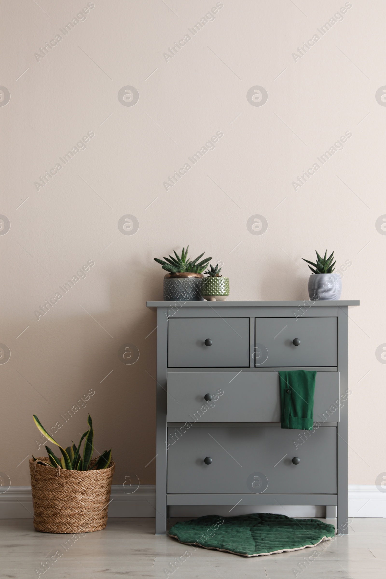 Photo of Room interior with grey chest of drawers near beige wall