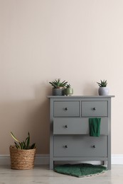 Photo of Room interior with grey chest of drawers near beige wall