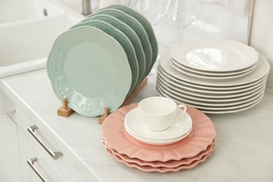 Clean plates, cup and glasses on white marble countertop in kitchen