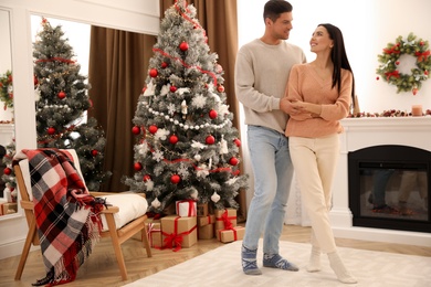 Happy couple dancing near Christmas tree at home