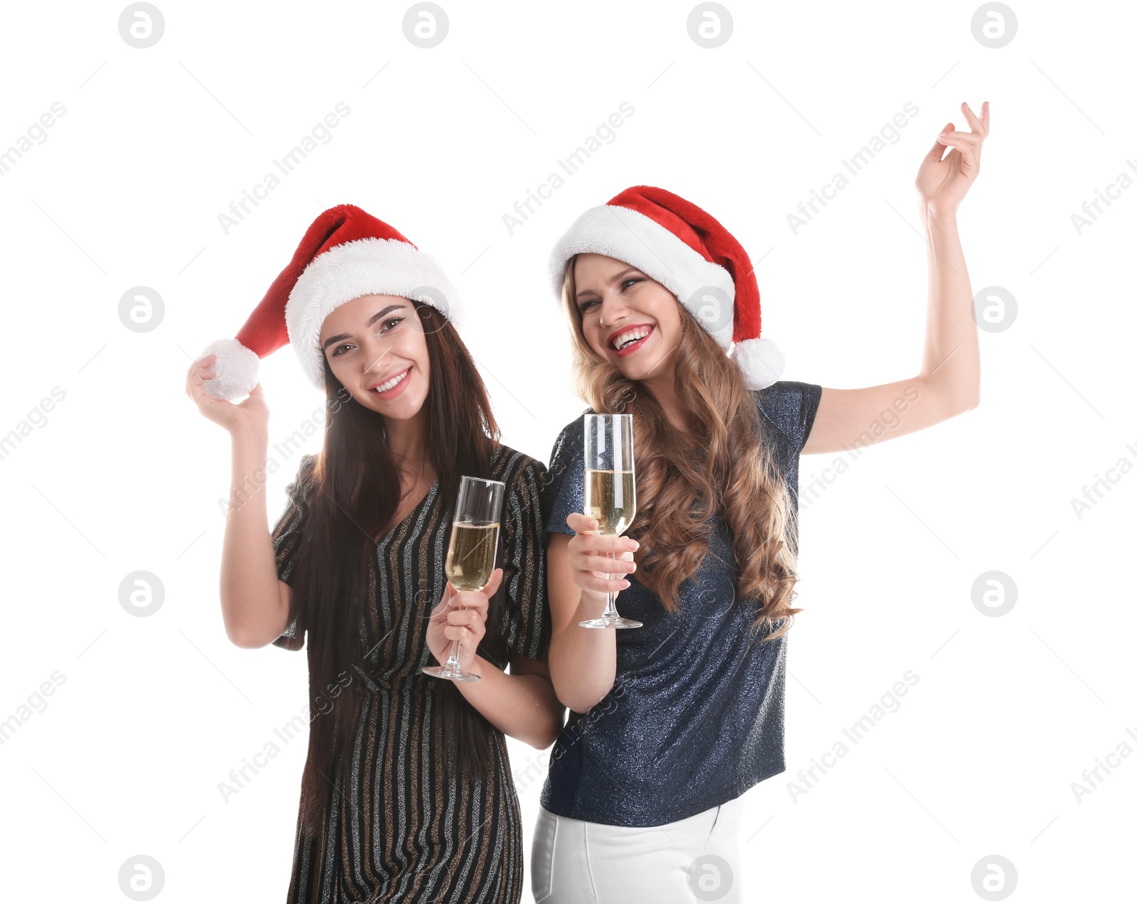 Photo of Beautiful young women in Santa hats with glasses of champagne on white background. Christmas celebration