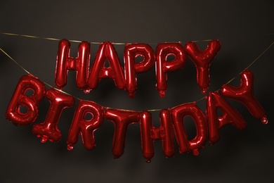 Phrase HAPPY BIRTHDAY made of red balloon letters on dark background