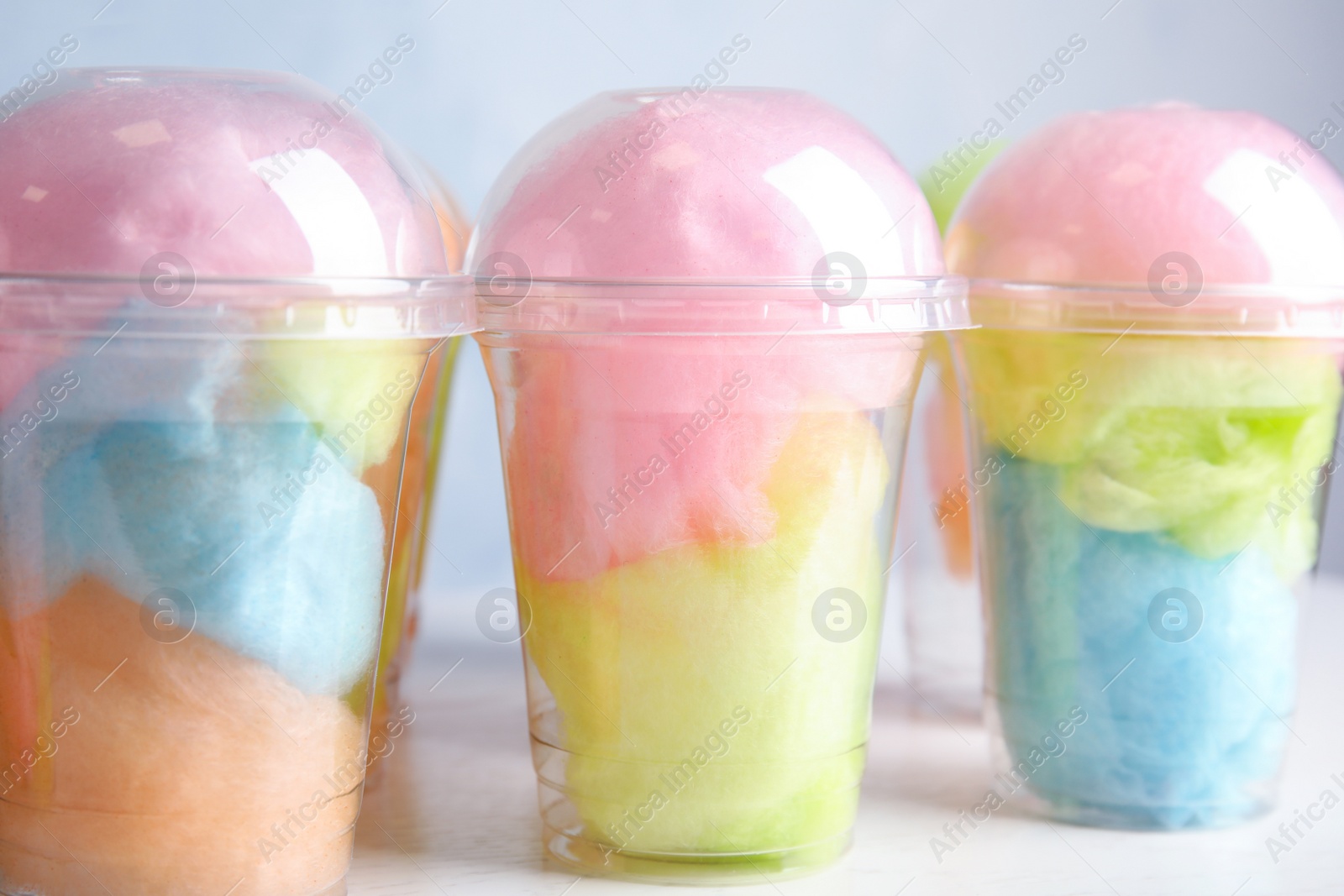 Photo of Many plastic cups with tasty cotton candies on white wooden table