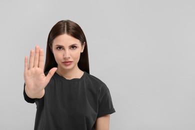 Photo of Woman showing stop gesture on grey background, space for text