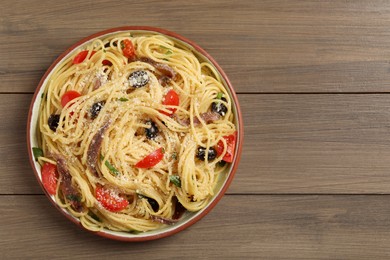 Photo of Plate of delicious pasta with anchovies, tomatoes and parmesan cheese on wooden table, top view. Space for text