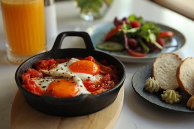 Photo of Tasty Shakshouka served on white table. Traditional Arabic dish