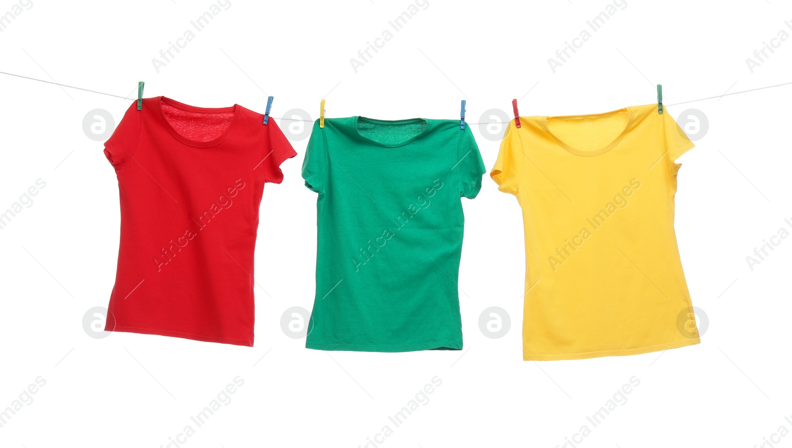 Photo of Different bright t-shirts drying on washing line against white background