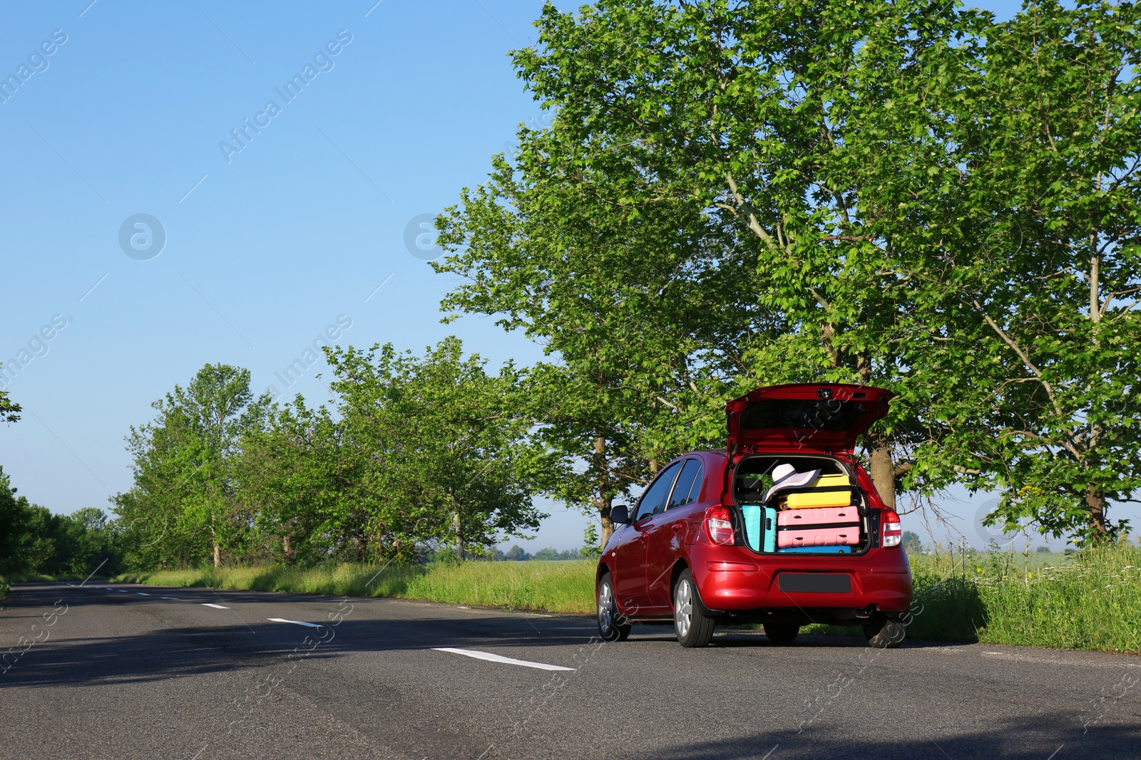 Photo of Family car with open trunk full of luggage on highway. Space for text