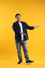 Photo of Full length portrait of happy man showing something on yellow background