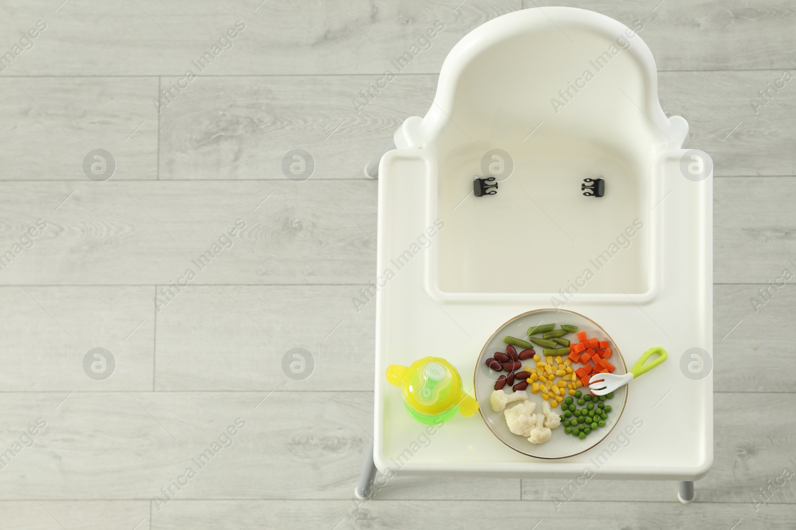 Photo of Baby high chair with healthy food and water, top view. Space for text