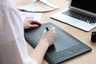 Photo of Professional designer with graphic tablet at wooden table, closeup