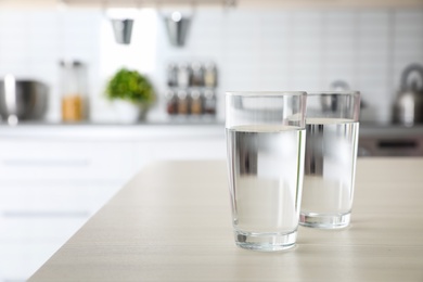 Photo of Glasses of fresh water on table indoors. Space for text