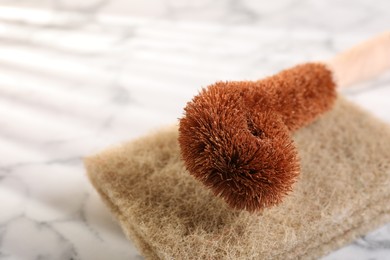 One cleaning brush and sponges on white marble table, closeup. Space for text