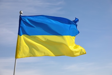 National flag of Ukraine against blue sky, closeup