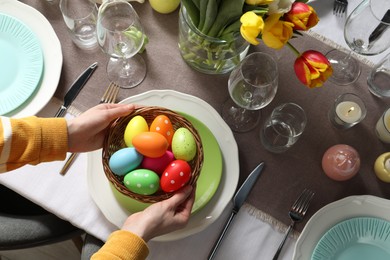 Photo of Woman setting table for festive Easter dinner at home, top view