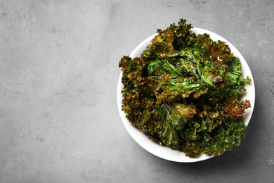 Photo of Tasty kale chips with seeds on grey table, top view. Space for text