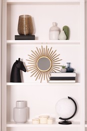 Photo of Interior design. Shelves with stylish accessories and books near white wall